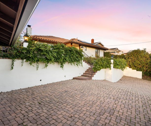 A quaint pathway beside a residential building, accompanied by a staircase ascending upwards