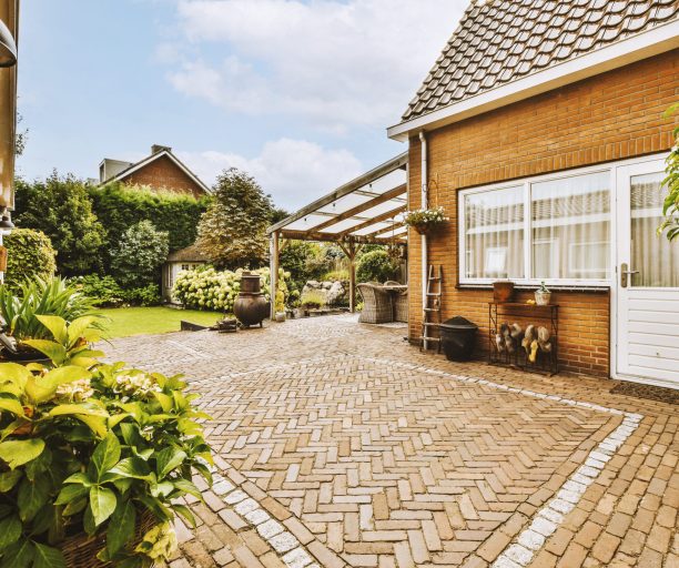 Neat paved patio with sitting area and small garden near wooden fence